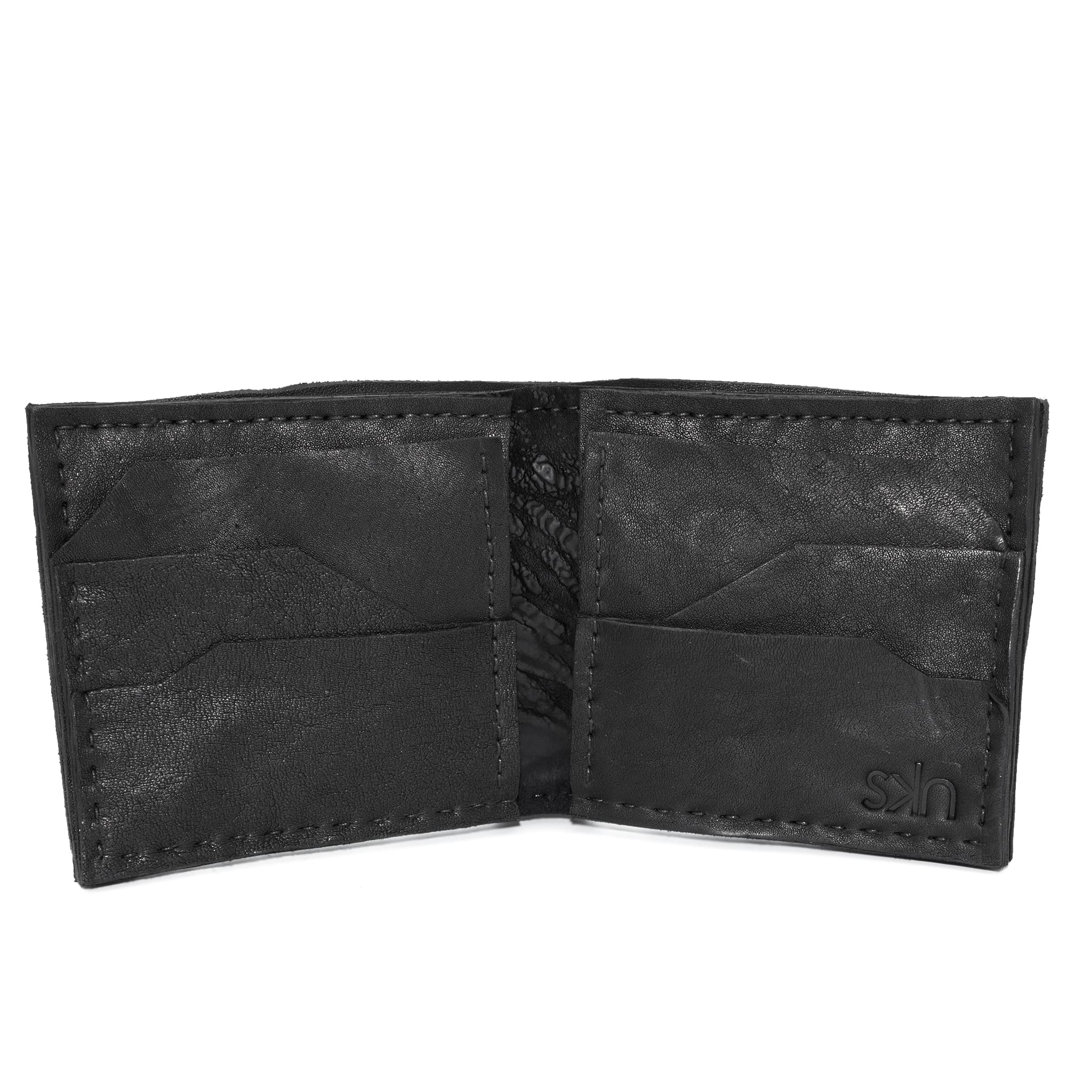 a closed seam 8 pocket bifold wallet crafted from a butter soft reverse culatta leather with a matte black object dyed finish. a riri zipper pocket is adorned with a hand forged solid .925sterling silver zipper pull available to buy online from artisanal leather studio atelierskn.com