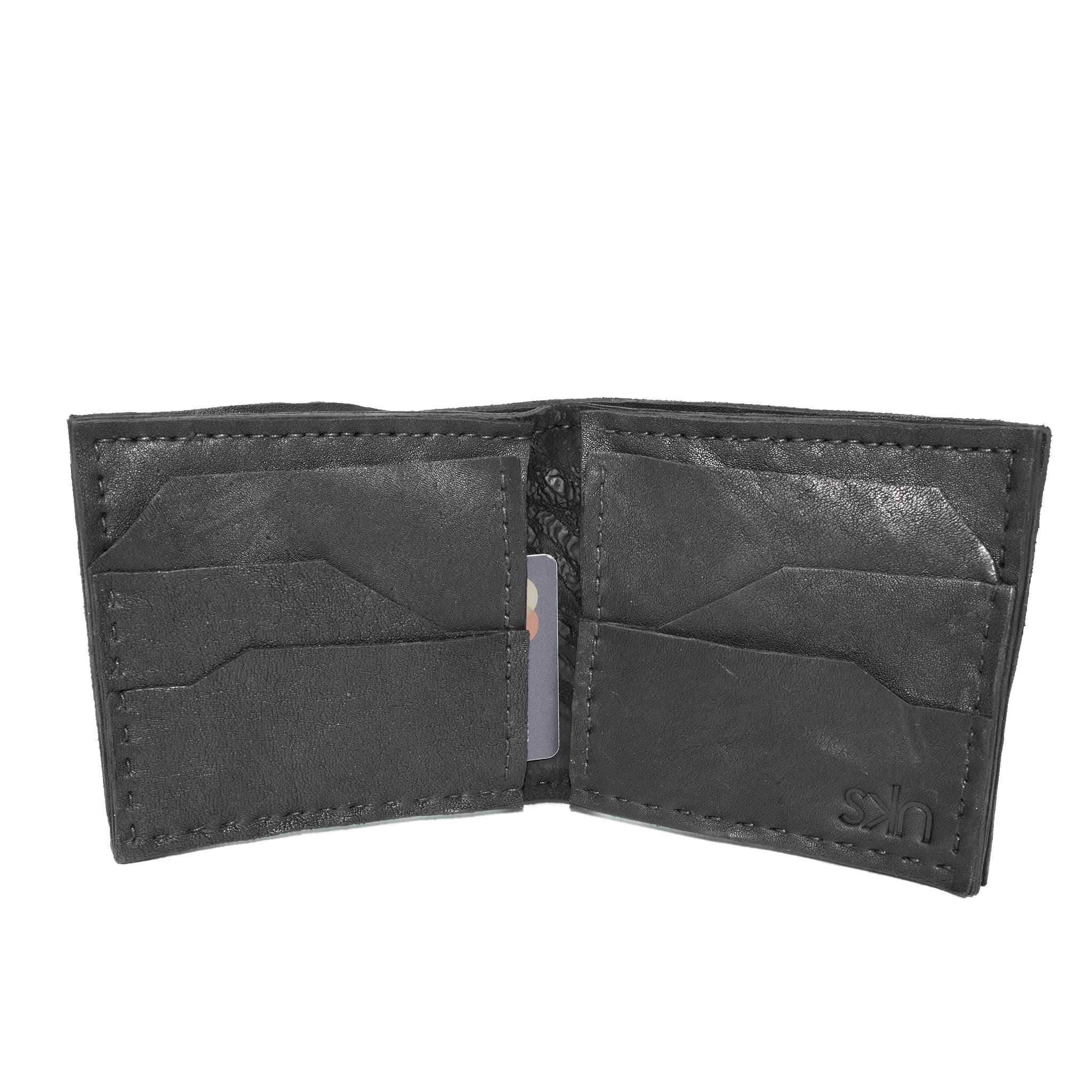 a closed seam 8 pocket bifold wallet crafted from a butter soft reverse culatta leather with a matte black object dyed finish. a riri zipper pocket is adorned with a hand forged solid .925sterling silver zipper pull available to buy online from artisanal leather studio atelierskn.com