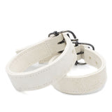 avant garde hand stitched horse culatta leather bicep belts, in a crushed bone finish. the arm cuffs feature a minimal silhouette with tonal japanese linen stitching and a hand forged .925 sterling silver buckle hardware. the arm belts are available to buy online from artisanal designer atelierskn.com 