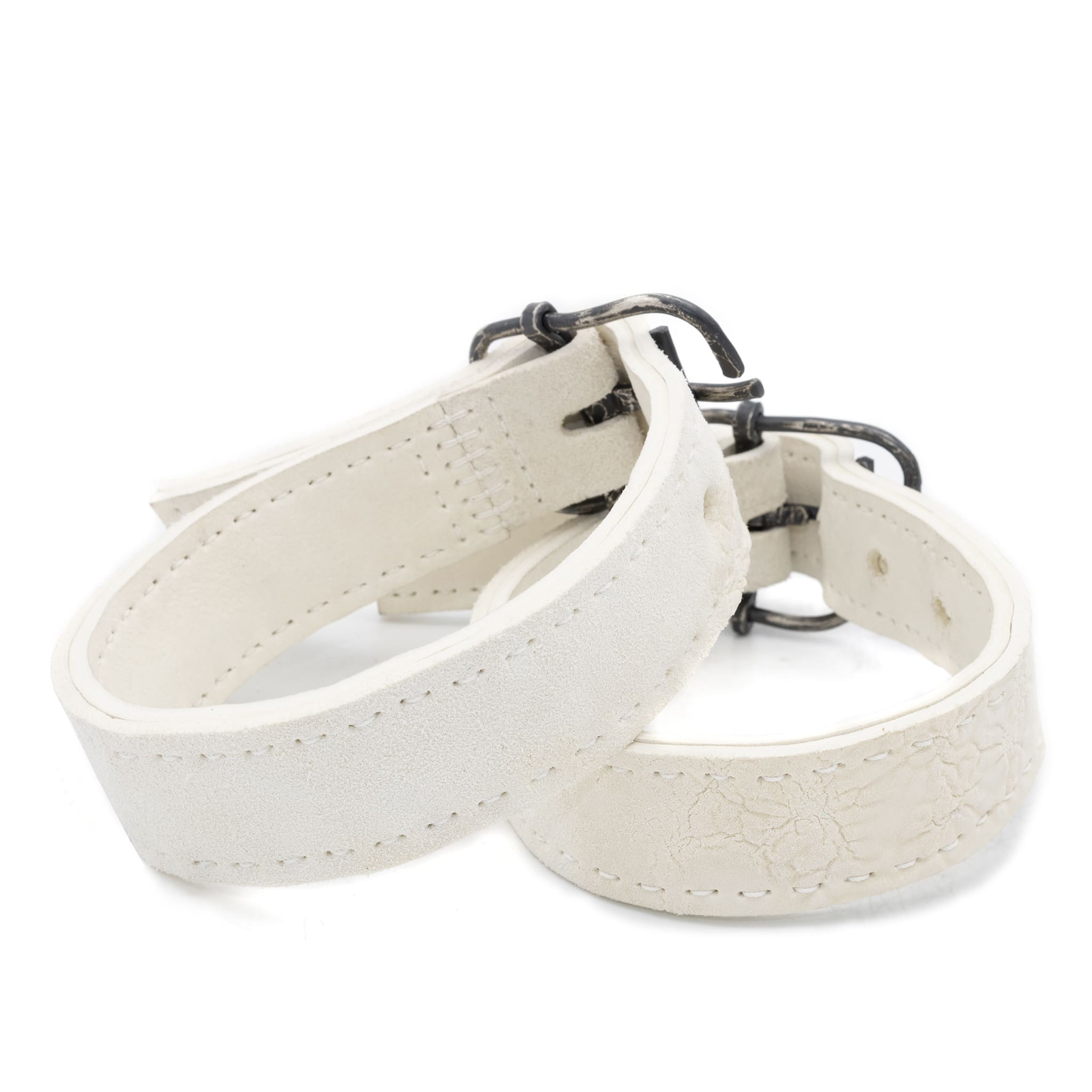 avant garde hand stitched horse culatta leather bicep belts, in a crushed bone finish. the arm cuffs feature a minimal silhouette with tonal japanese linen stitching and a hand forged .925 sterling silver buckle hardware. the arm belts are available to buy online from artisanal designer atelierskn.com 