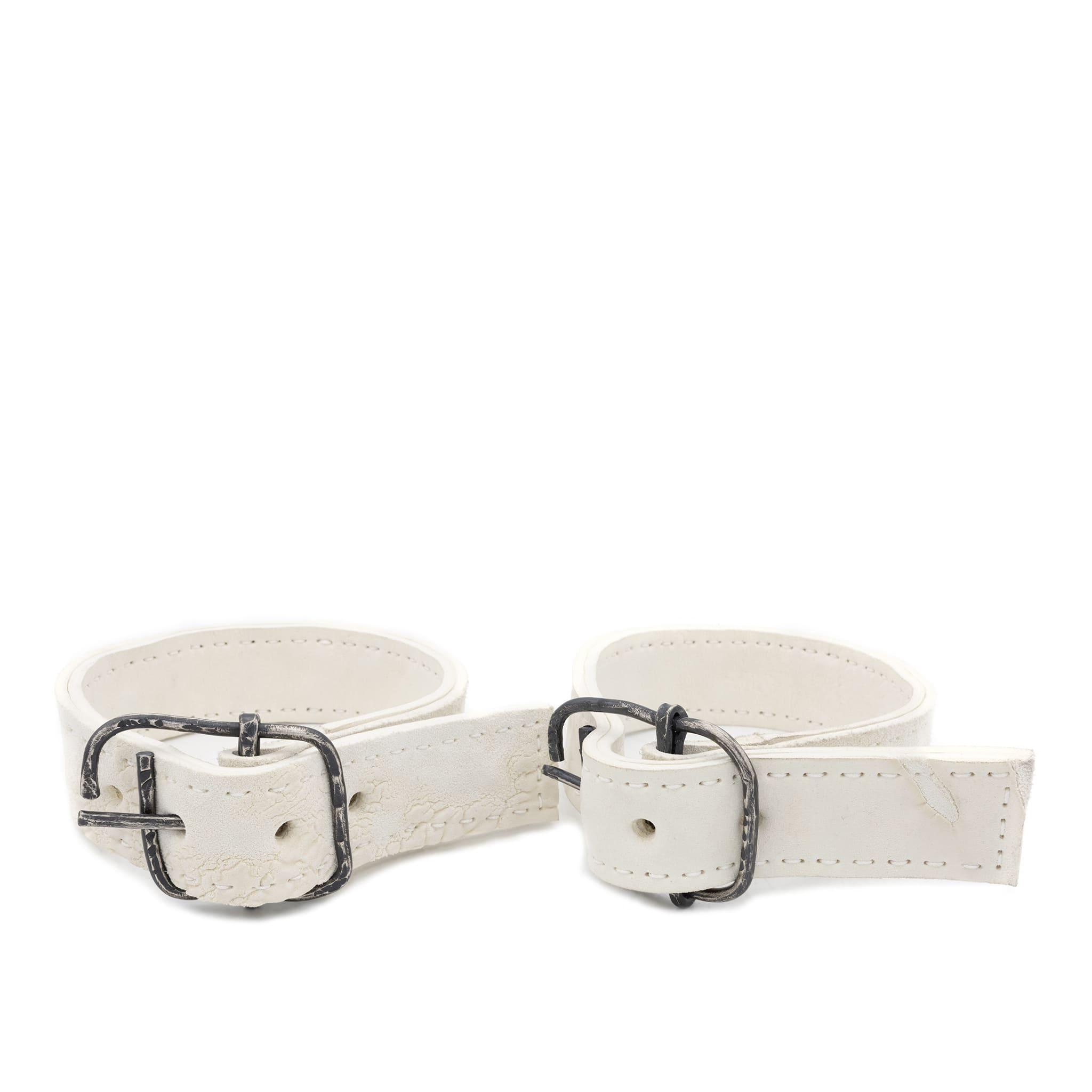 avant garde hand stitched horse culatta leather bicep belts, in a crushed bone finish. the arm cuffs feature a minimal silhouette with tonal japanese linen stitching and a hand forged .925 sterling silver buckle hardware. the arm belts are available to buy online from artisanal designer atelierskn.com 