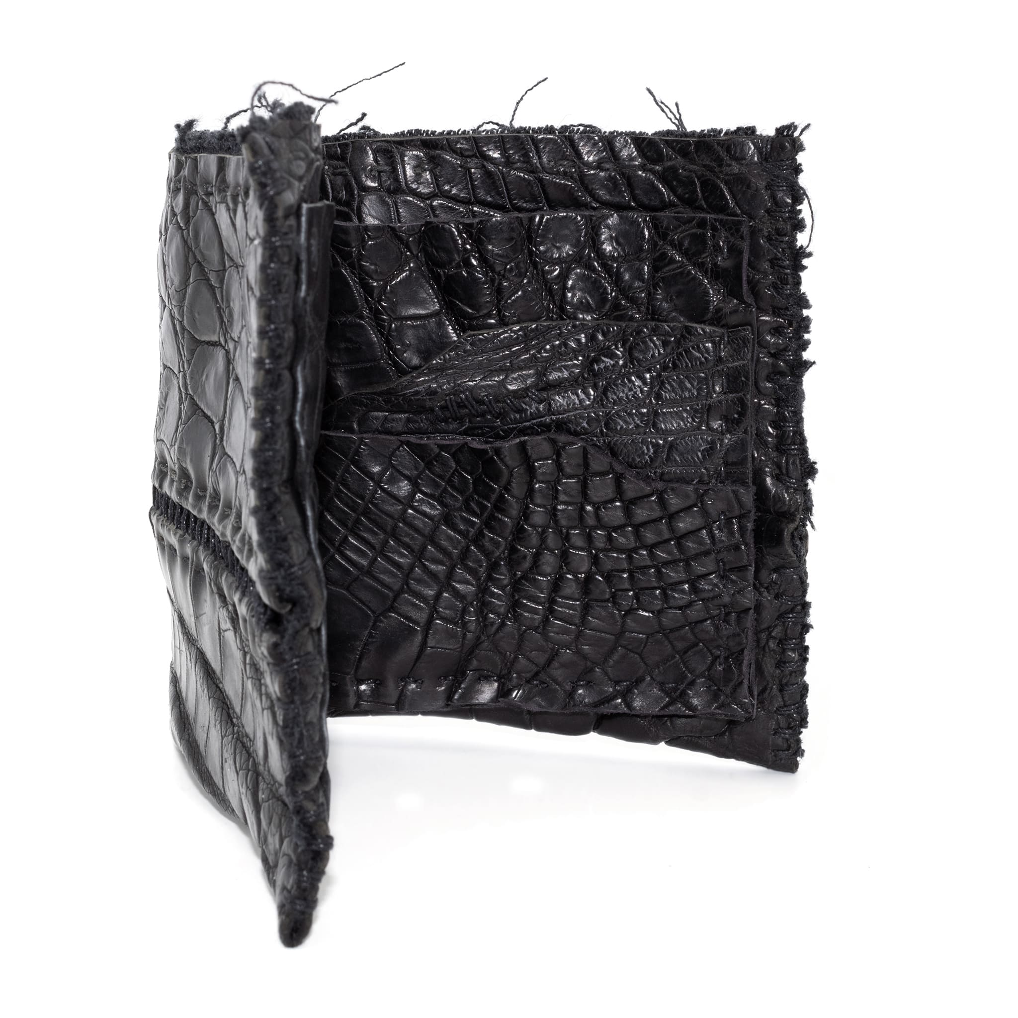 black crocodile leather wallet hand stitched over a 10 hour period. the genuine crocodile leather bifold wallet features multiple card slots, and a japanese ramie lining. an open seam construction and overlocked sides are hand stitched in a japanese linen thread. the wallet is available to buy online from avant garde leather studio atelierskn.com