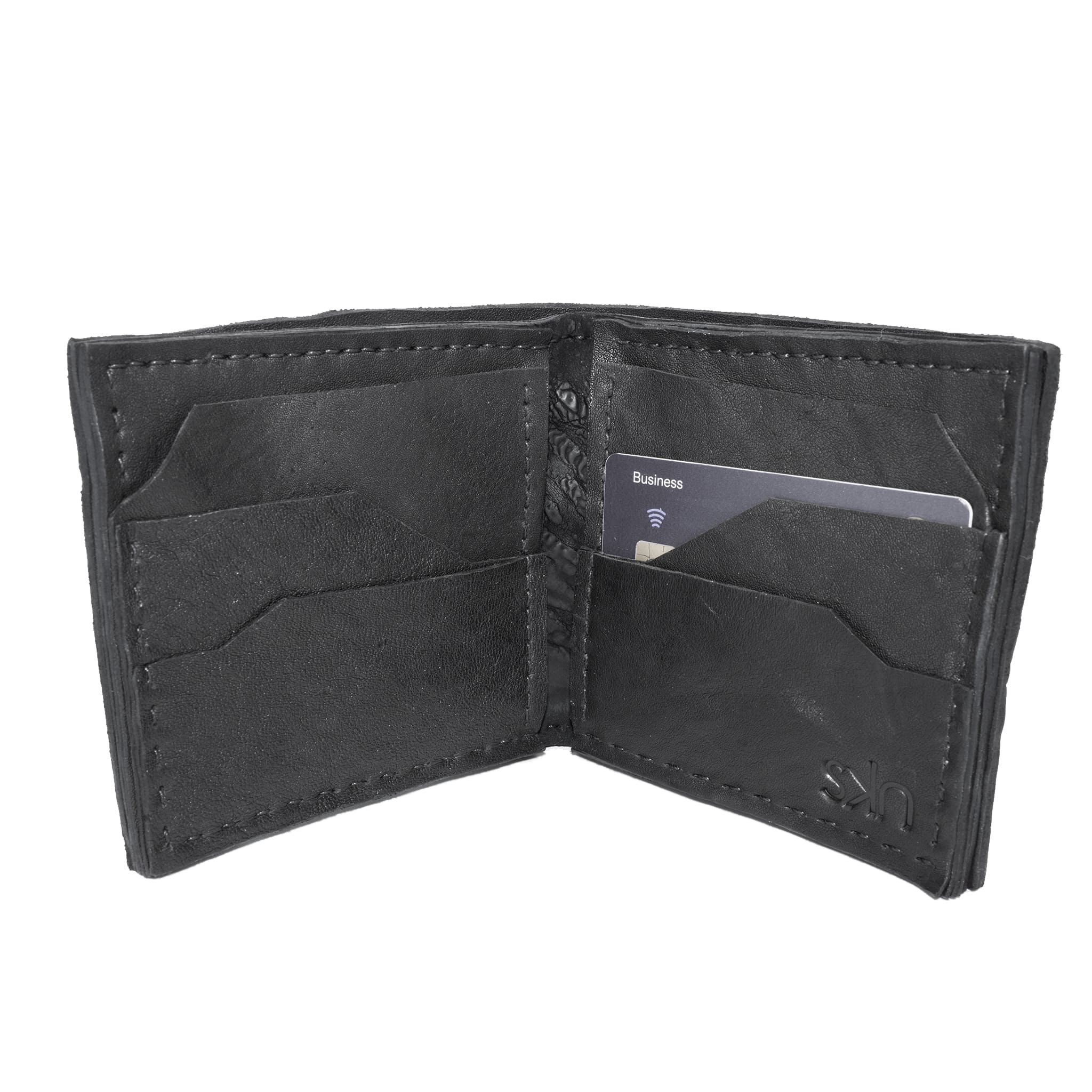 a closed seam 8 pocket bifold wallet crafted from a butter soft reverse culatta leather with a matte black object dyed finish. a riri zipper pocket is adorned with a hand forged solid .925sterling silver zipper pull available to buy online from artisanal leather studio atelierskn.com