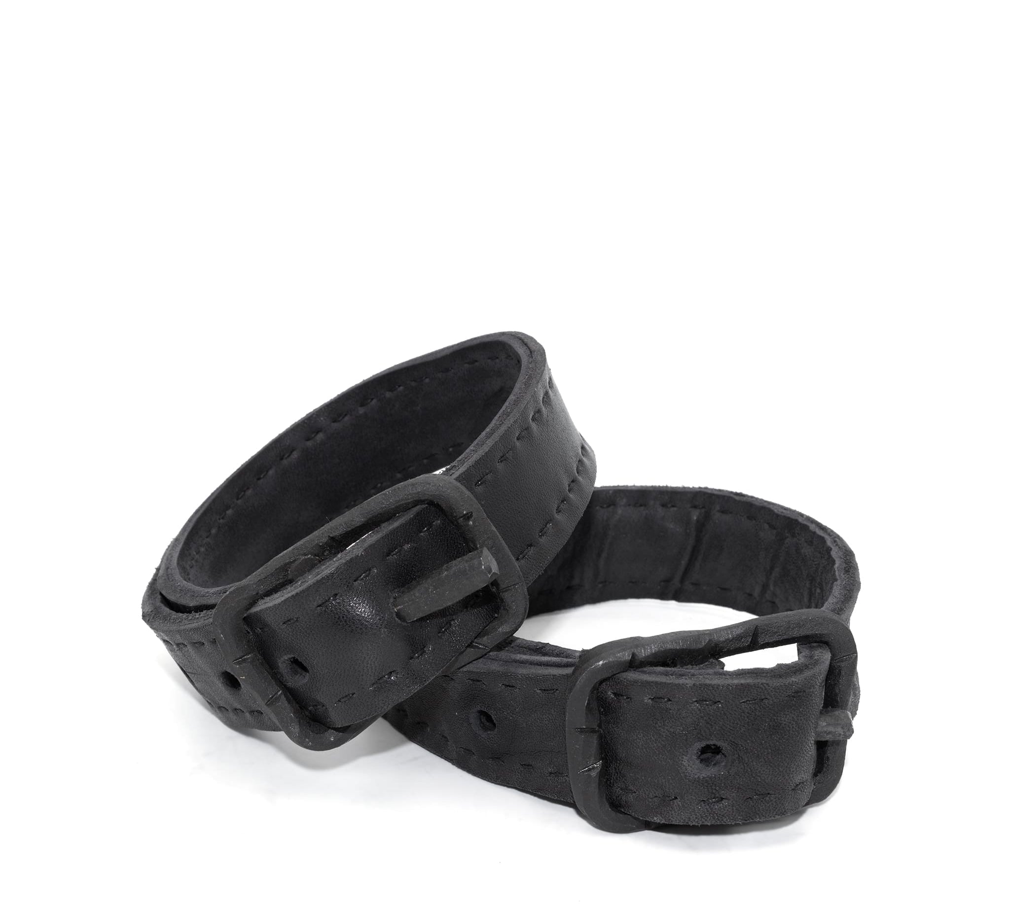 avant garde hand stitched horse culatta leather bicep belts, with an iron dye finish. the arm cuffs feature a minimal silhouette with tonal japanese linen stitching and hand forged iron buckle hardware. the arm belts are available to buy online from artisanal designer atelierskn.com 