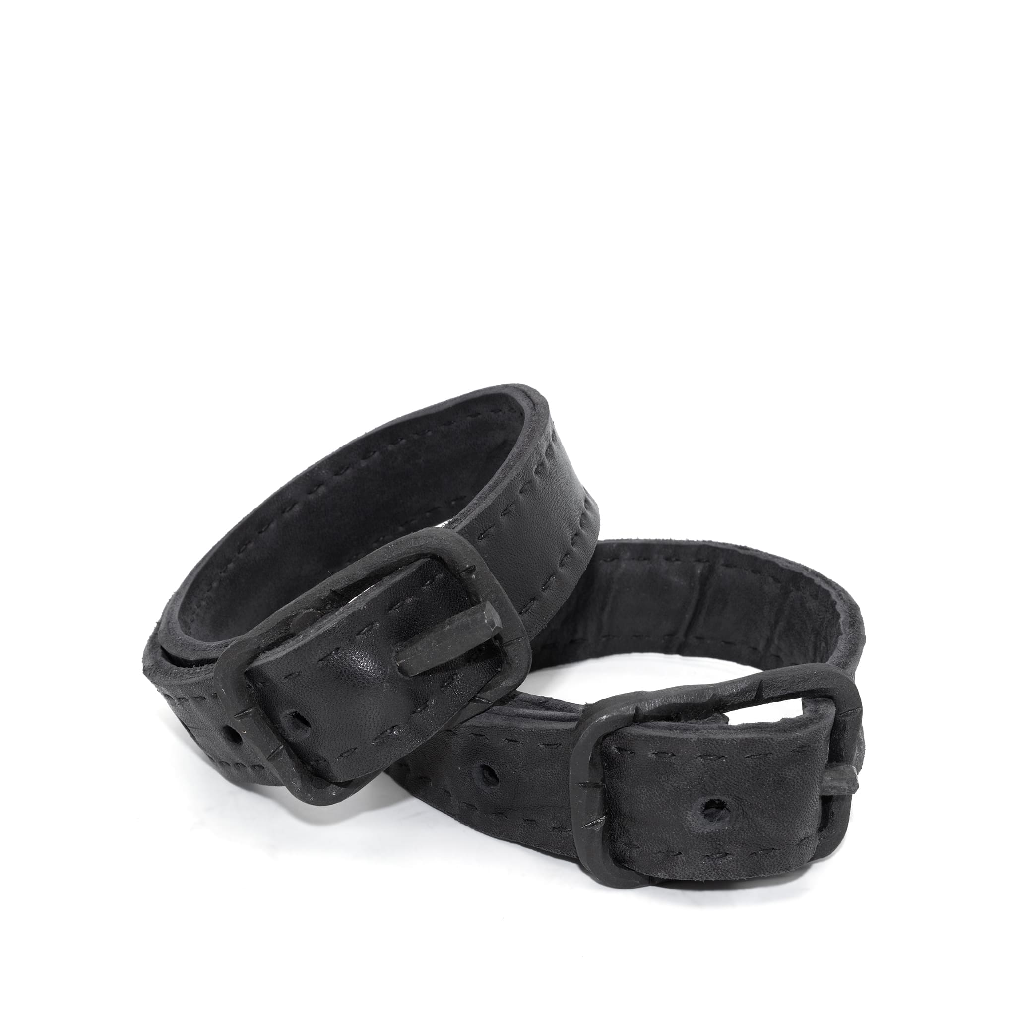 avant garde hand stitched horse culatta leather bicep belts, with an iron dye finish. the arm cuffs feature a minimal silhouette with tonal japanese linen stitching and hand forged iron buckle hardware. the arm belts are available to buy online from artisanal designer atelierskn.com 