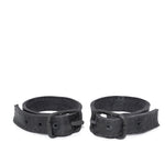 avant garde hand stitched horse culatta leather bicep belts, with an iron dye finish. the arm cuffs feature a minimal silhouette with tonal japanese linen stitching and hand forged iron buckle hardware. the arm belts are available to buy online from artisanal designer atelierskn.com 