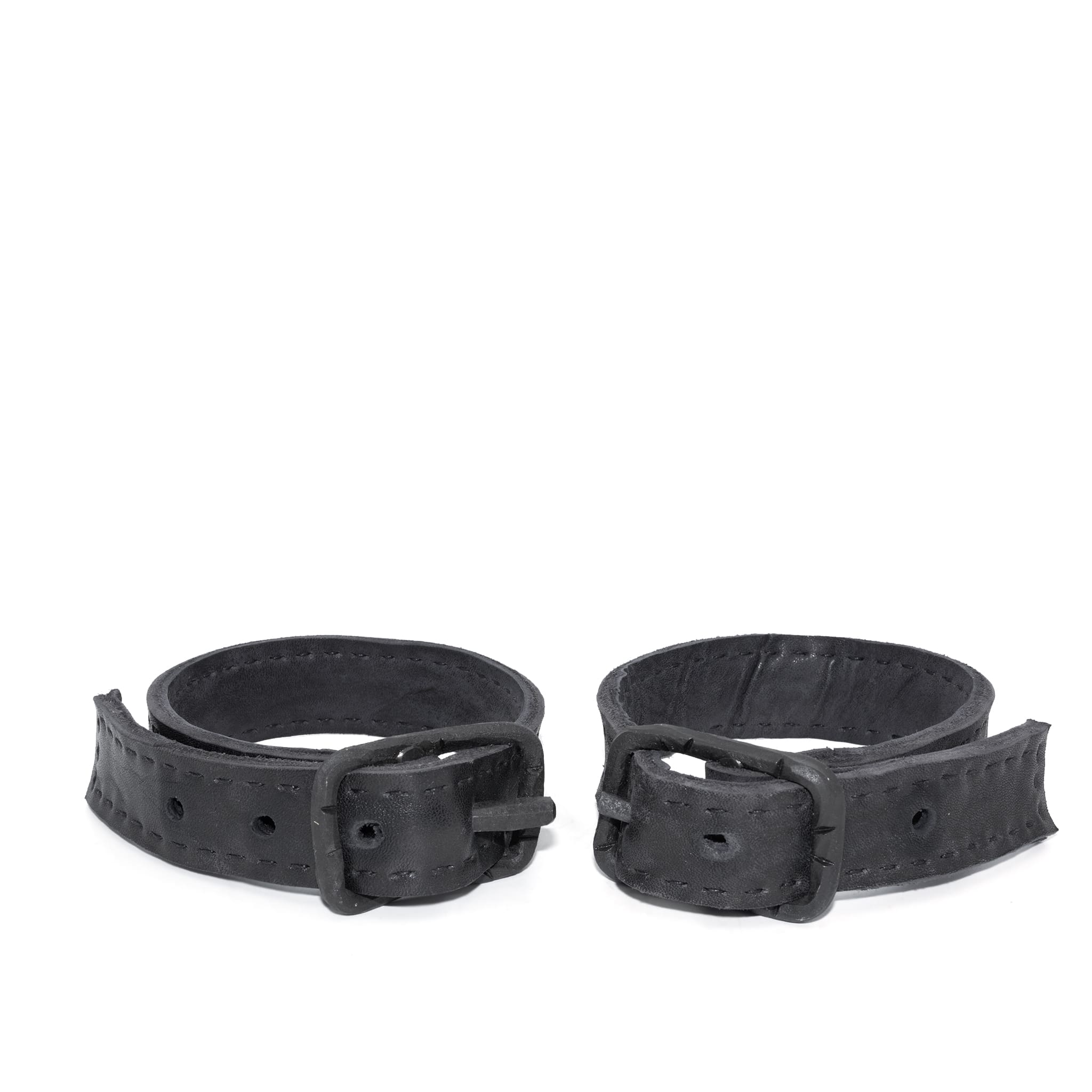 avant garde hand stitched horse culatta leather bicep belts, with an iron dye finish. the arm cuffs feature a minimal silhouette with tonal japanese linen stitching and hand forged iron buckle hardware. the arm belts are available to buy online from artisanal designer atelierskn.com 