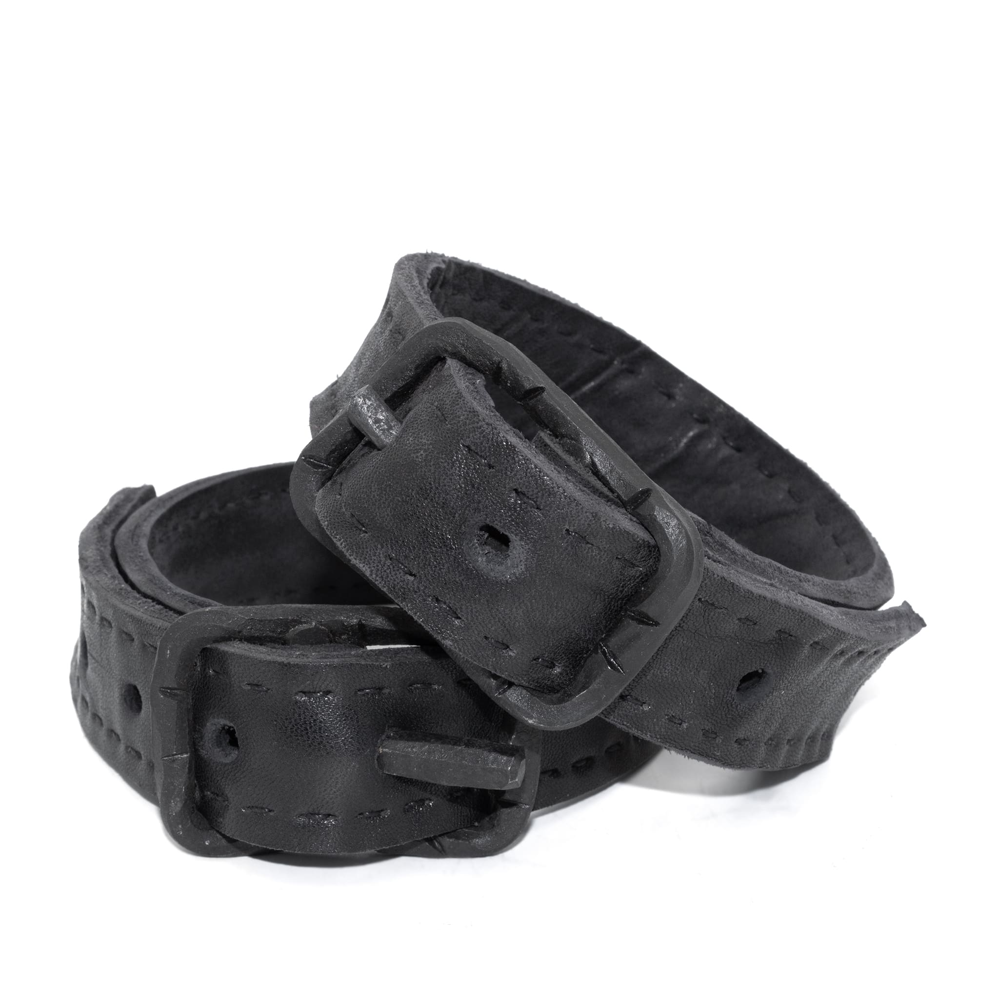 avant garde hand stitched horse culatta leather bicep belts, with an iron dye finish. the arm cuffs feature a minimal silhouette with tonal japanese linen stitching and hand forged iron buckle hardware. the arm belts are available to buy online from artisanal designer atelierskn.com 