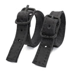 avant garde hand stitched horse culatta leather bicep belts, with an iron dye finish. the arm cuffs feature a minimal silhouette with tonal japanese linen stitching and hand forged iron buckle hardware. the arm belts are available to buy online from artisanal designer atelierskn.com 