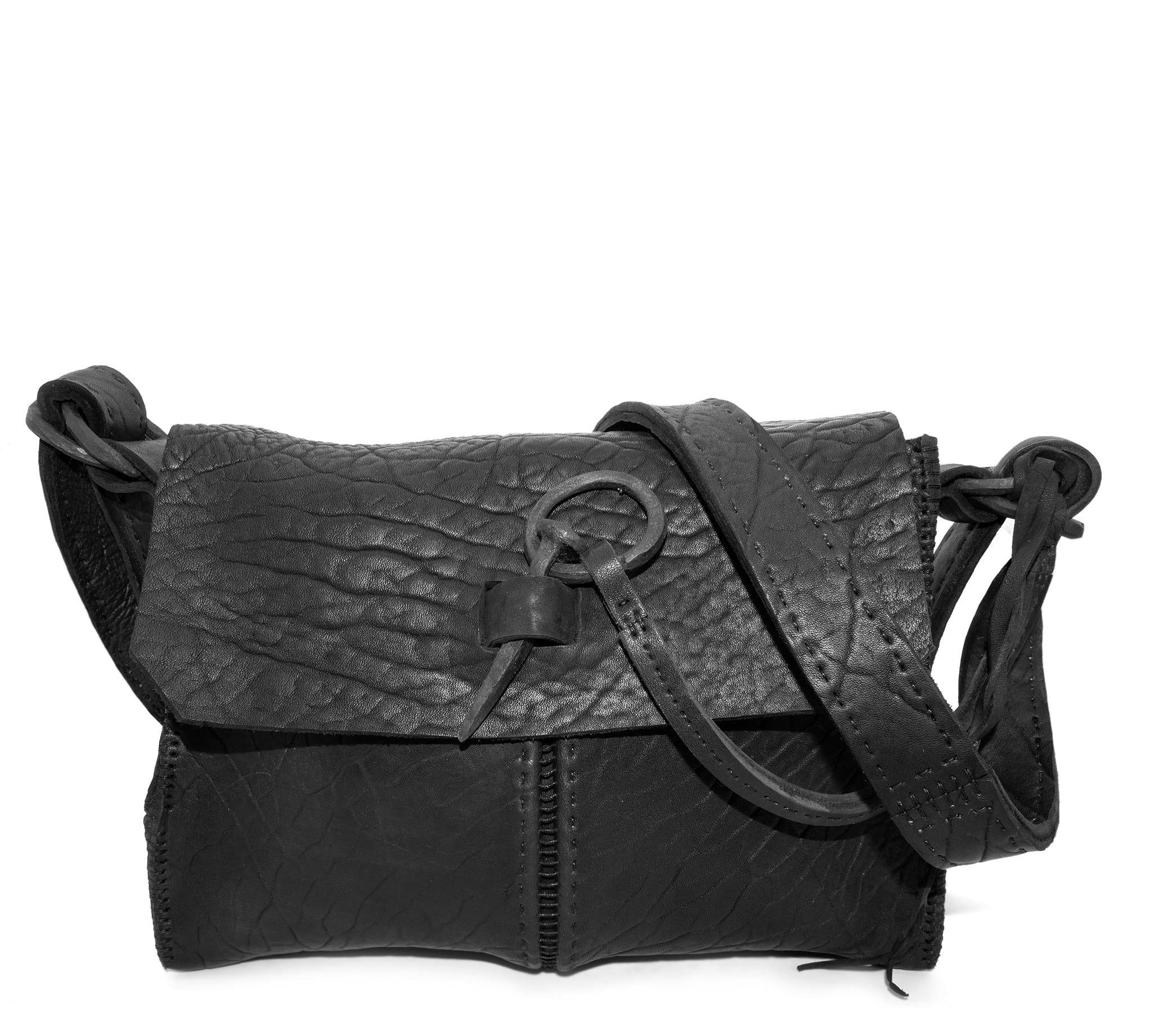 medium sized hand stitched washed horse culatta leather shoulder bag with an object dyed matte black finish. the bag features an open seam construction with a flap closure, riri zipper fastening and hand forged iron and silver hardware. the black leather bag is finished with an adjustable leather strap and is available to buy online from avant garde leather studio atelierskn.com.