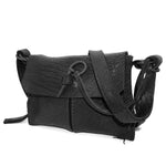 medium sized hand stitched washed horse culatta leather shoulder bag with an object dyed matte black finish. the bag features an open seam construction with a flap closure, riri zipper fastening and hand forged iron and silver hardware. the black leather bag is finished with an adjustable leather strap and is available to buy online from avant garde leather studio atelierskn.com.