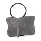 meticulously hand stitched kudu leather bag with a zipper fastening and large iron ring carry handle. an adjustable double layered shoulder strap is adorned with a distressed clip. the bag is available to buy online from uk based avant garde leather studio telierskn.com