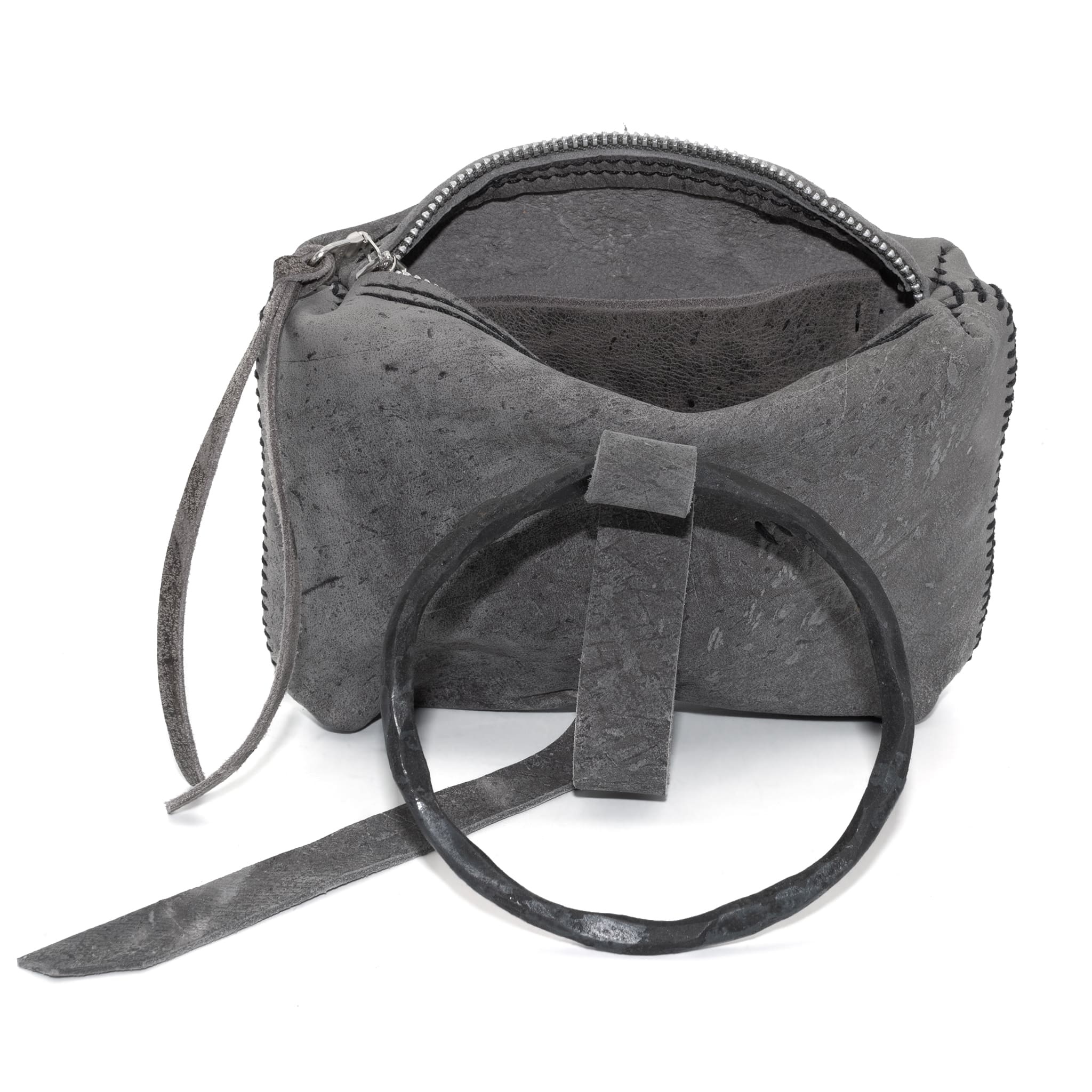 meticulously hand stitched kudu leather bag with a zipper fastening and large iron ring carry handle. an adjustable double layered shoulder strap is adorned with a distressed clip. the bag is available to buy online from uk based avant garde leather studio telierskn.com