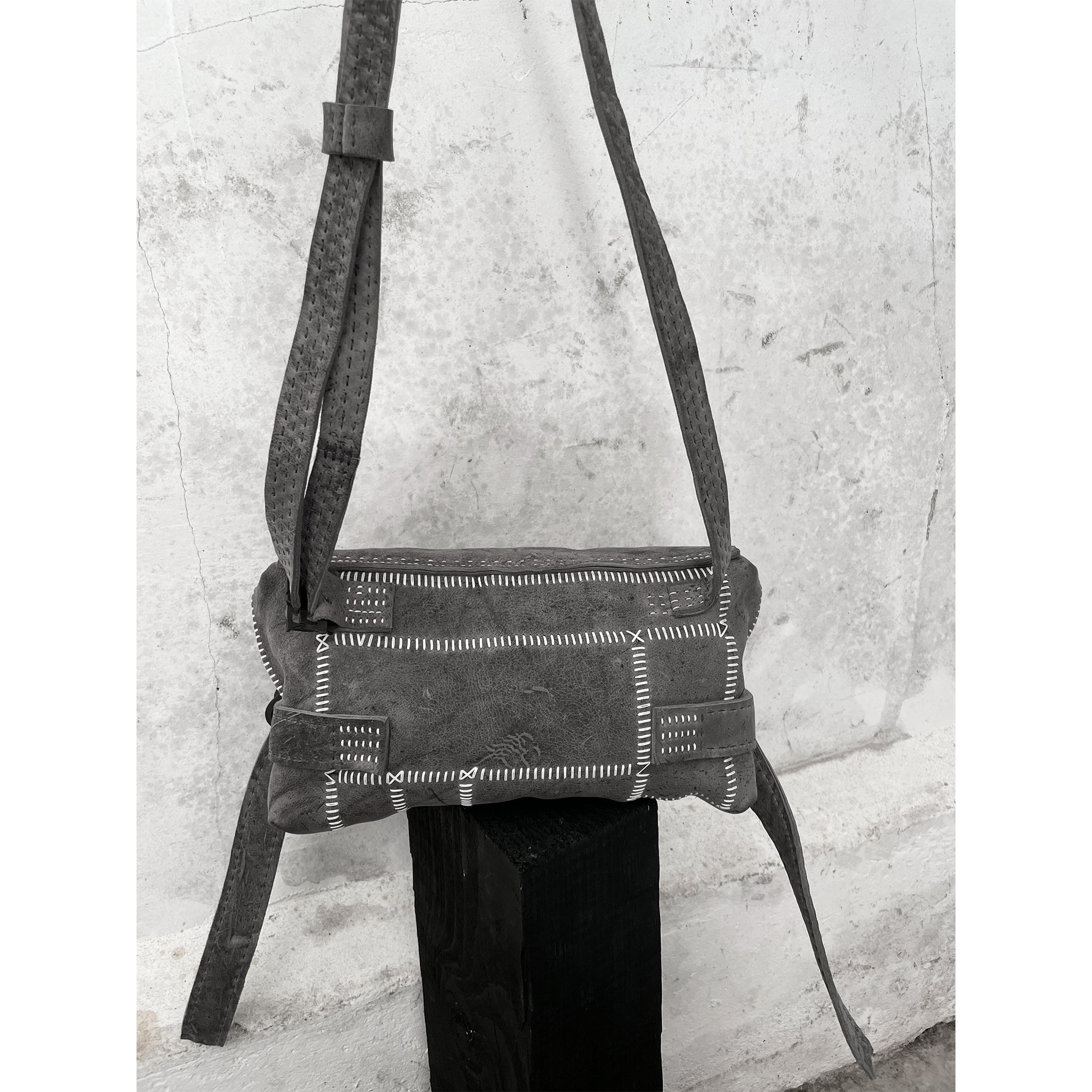 avant garde hand stitched patchwork shoulder bag in a soft kudu leather. the bag features a zipper closure, hand forged iron hardware and an adjustable shoulder strap. the bag has been hand sewn without the use of machines and is available to buy online from artisanal leather studio atelierskn.com.