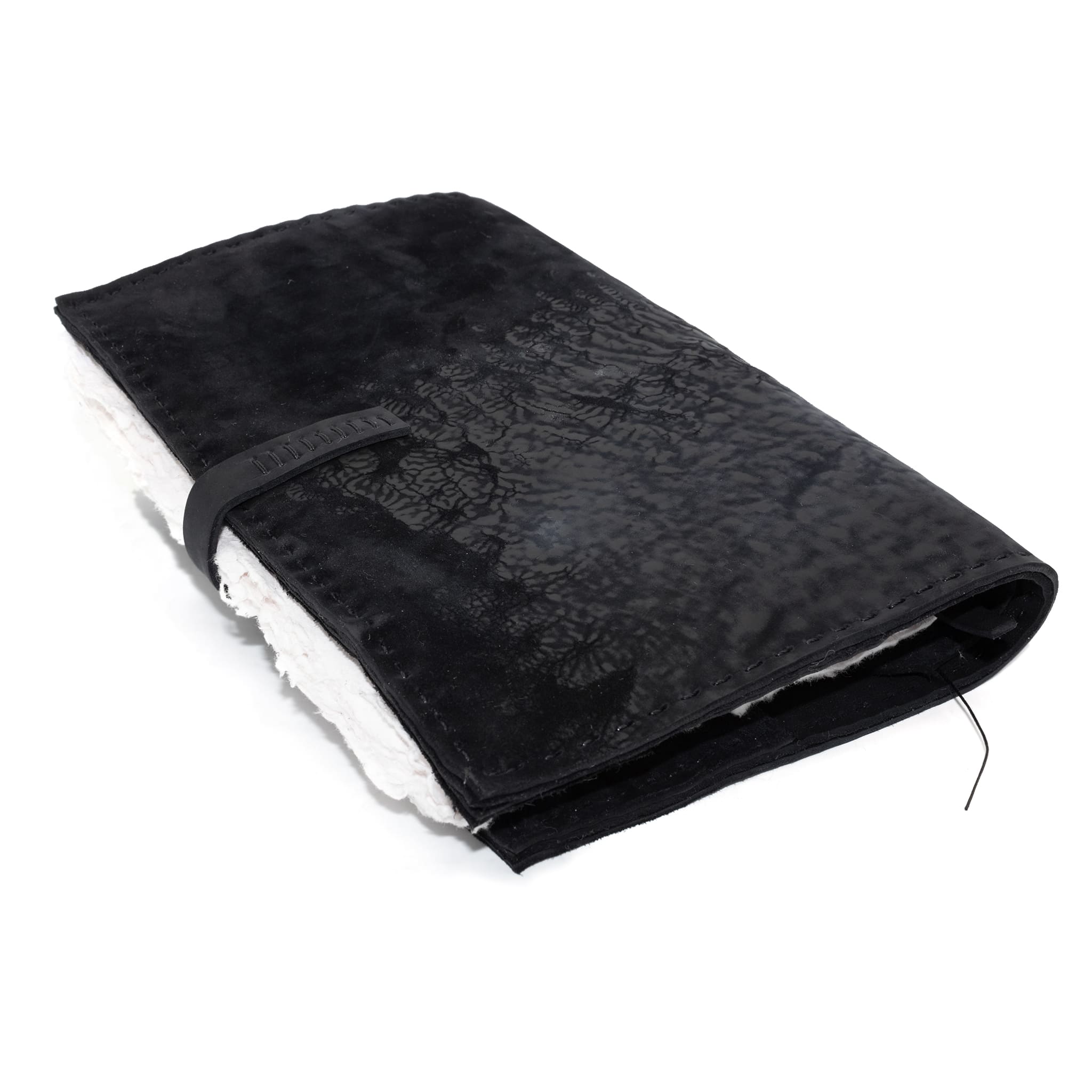 Hand stitched matte black reverse horse culatta leather journal cover with a hand forged solid .925 sterling silver buckle closure and multiple pages of 150gsm handmade cotton rag paper. available to buy online from artisanal uk based leather studio atelier skn.