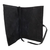 Hand stitched matte black reverse horse culatta leather journal cover with a hand forged solid .925 sterling silver buckle closure and multiple pages of 150gsm handmade cotton rag paper. available to buy online from artisanal uk based leather studio atelier skn.