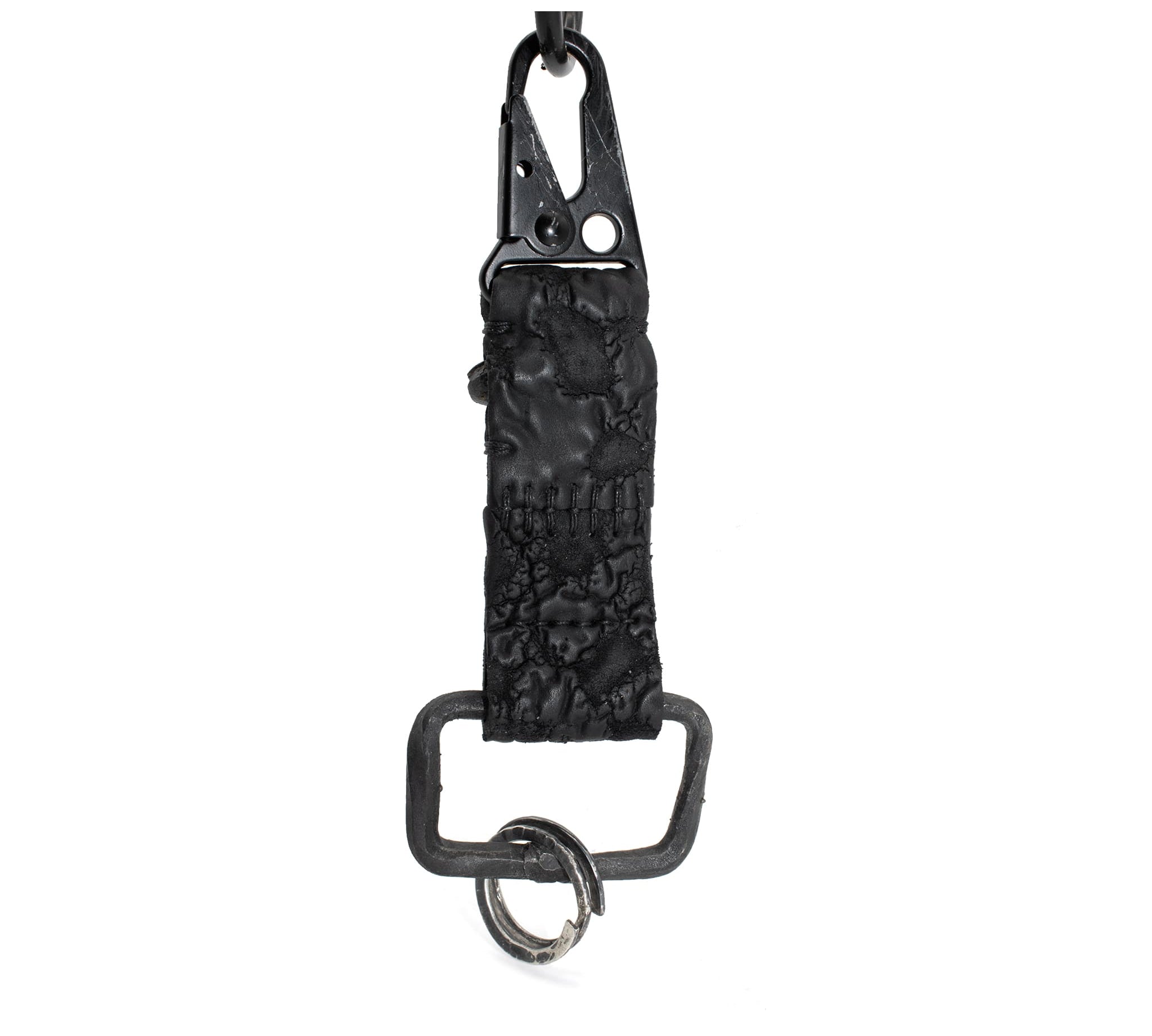 hand stitched and hand dyed reverse horse culatta leather keychain adorned with hand forged iron and .925 sterling silver hardware. a distressed military clip and overlock stitching finish off the keychain. available online from artisanal leather studio atelier skn.