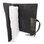 Hand stitched object dyed grey reverse horse culatta leather journal cover with a hand forged solid burnt bronze nail closure, interior pockets and multiple pages of 150gsm handmade cotton rag paper. available to buy online from artisanal uk based leather studio atelier skn.